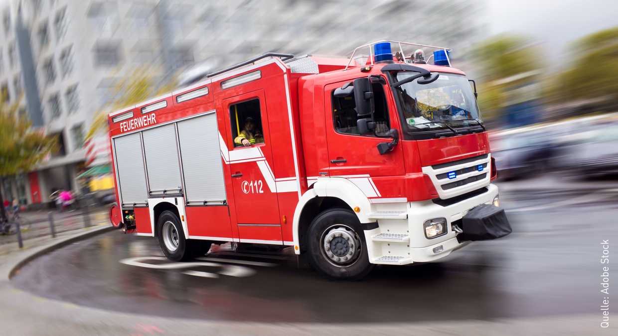 Ein Feuerwehrwagen fährt mit hoher Geschwindigkeit. Das Bild ist aufgrund der dargestellten Geschwindigkeit verwischt.