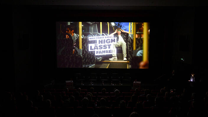 Kinoleinwand mit dem Bild: Junger Mann im Bus. Zu der Claim: High fährt nicht. High lässt fahren.