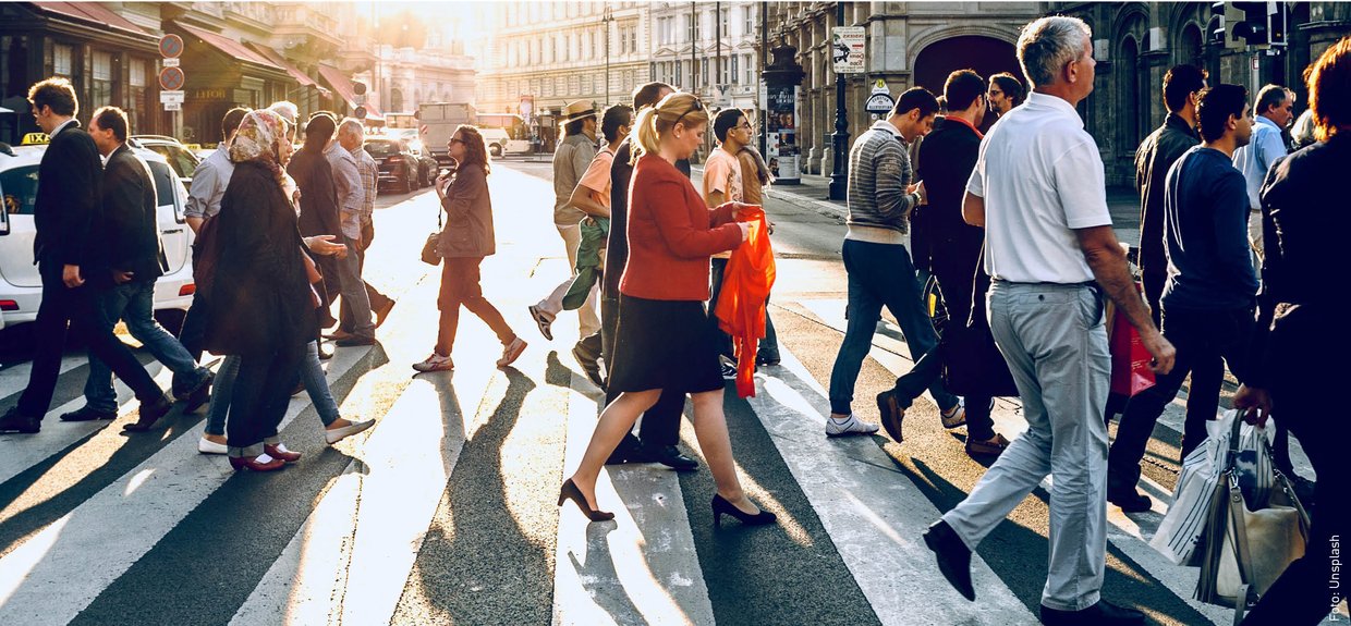 Fußverkehr, Zebrastreifen. Viele Menschen laufen in einer Stadt bei Sonnenuntergang über einen Zebrastreifen.