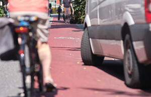 Ein Transport parkt auf einem Schutzstreifen. Eine herannahende Person auf einem Fahrrad muss ausweichen.