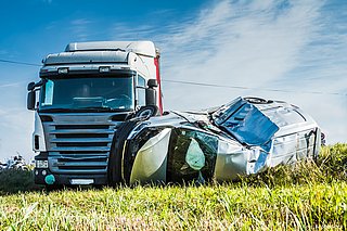 Links steht ein Lkw, rechts daneben liegt ein Auto, das verbeult ist.