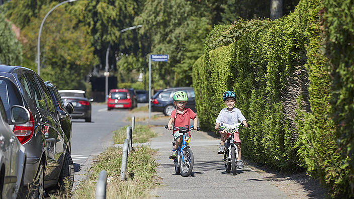Zwei Kinder im Kitaalter fahren auf einem Gehweg