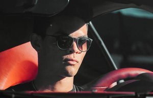 Ein Mann mit Sonnenbrille fährt ein Auto.