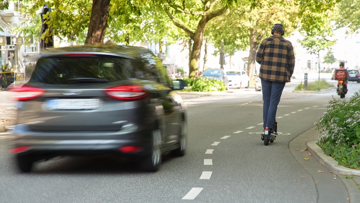 Auto überholt E-Scooter auf dem Radstreifen