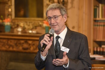 DVR-Präsident Prof. Dr. Walter Eichendorf trägt einen grauen Anzug mit leichten Streifen und einer Krawatte. In der Hand hält er ein Mikrofon.