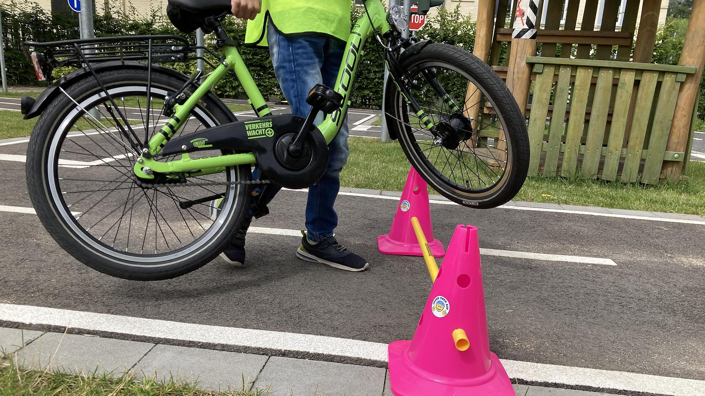 Ein Mann hebt ein Fahrrad über eine Stange im Parcours.