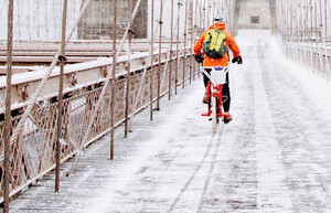 Ein Fahrradfahrer fährt über eine schneebedeckte Brücke.