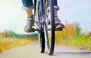 Eine Person fährt auf einem Feldweg, wobei nur die untere Hälfte vom Fahrrad und der Person abgebildet sind.
