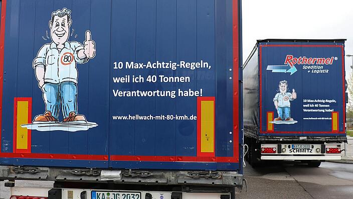 Auf dem Bild ist die Rückseite eines LKWs zu sehen, auf dem ein Bild von Max Achtzig zu sehen ist. Auf dem LKW steht: 10 Max-Achtzig-Regeln, weil ich 40 Tonnen Verantwortung habe!