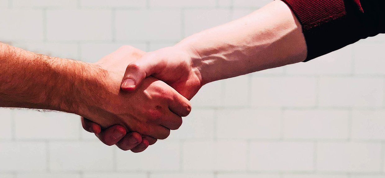 Hand reichen Zwei Männer geben sich die Hand.