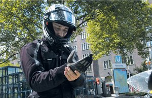 Mann stehend vor Motorrad in Motorradkleidung während er seinen Handschuh anzieht