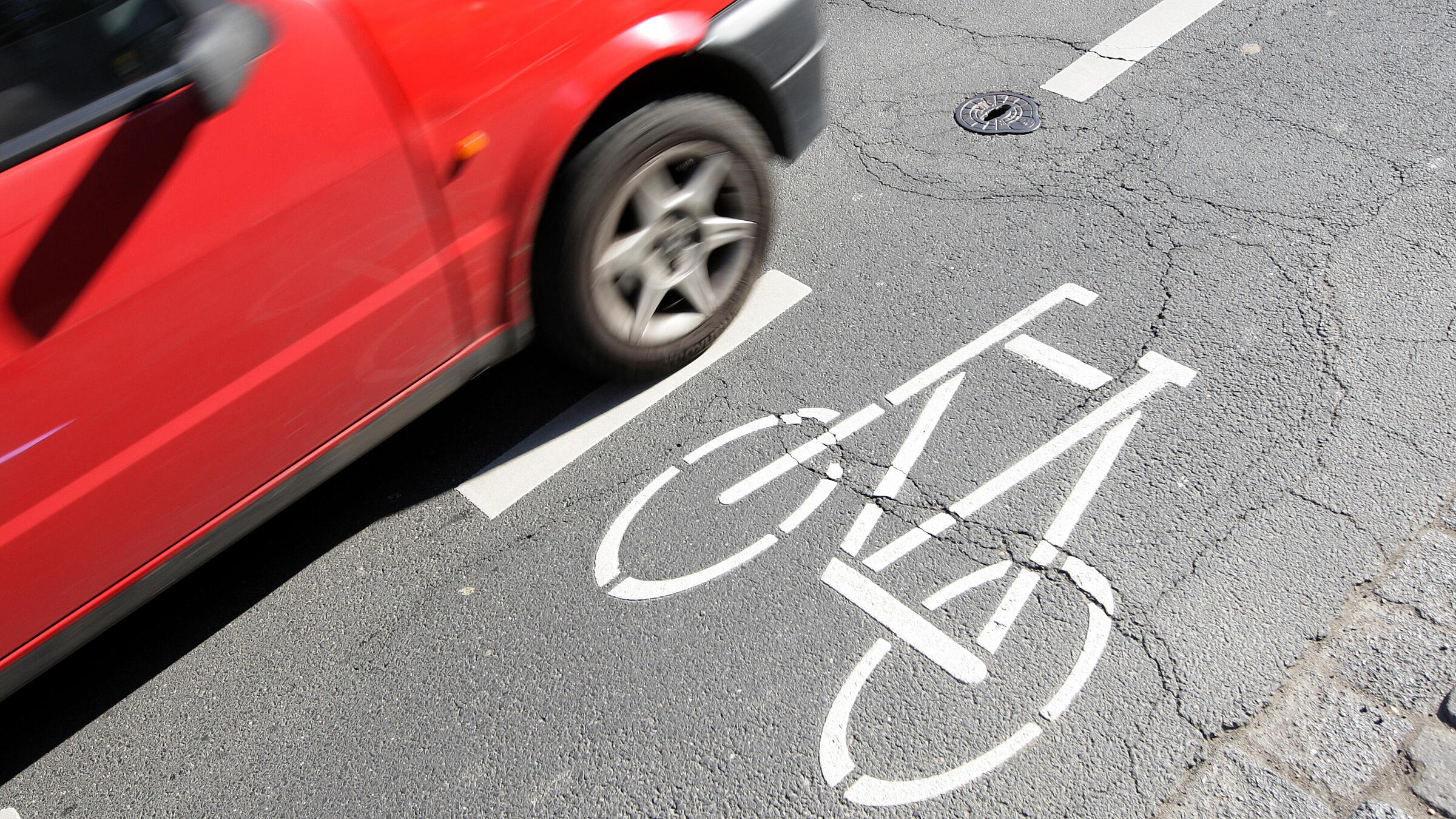 Ein Auto fährt sehr dicht neben einem Fahrradweg.