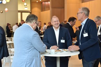 Drei Männer stehen an einem Stehtisch