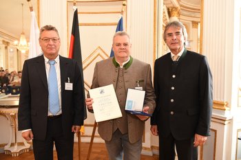Franz Weingartner, Foto: Tino Lex Drei Männer stehen nebeneinander, der mittlere hält eine Urkunde