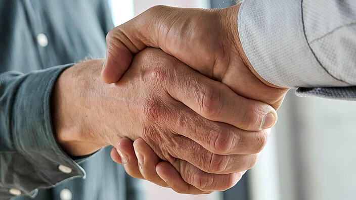 Two happy diverse professional business men executive leaders shaking hands at office meeting. Smiling businessman standing greeting partner with handshake. Leadership, trust, partnership concept.