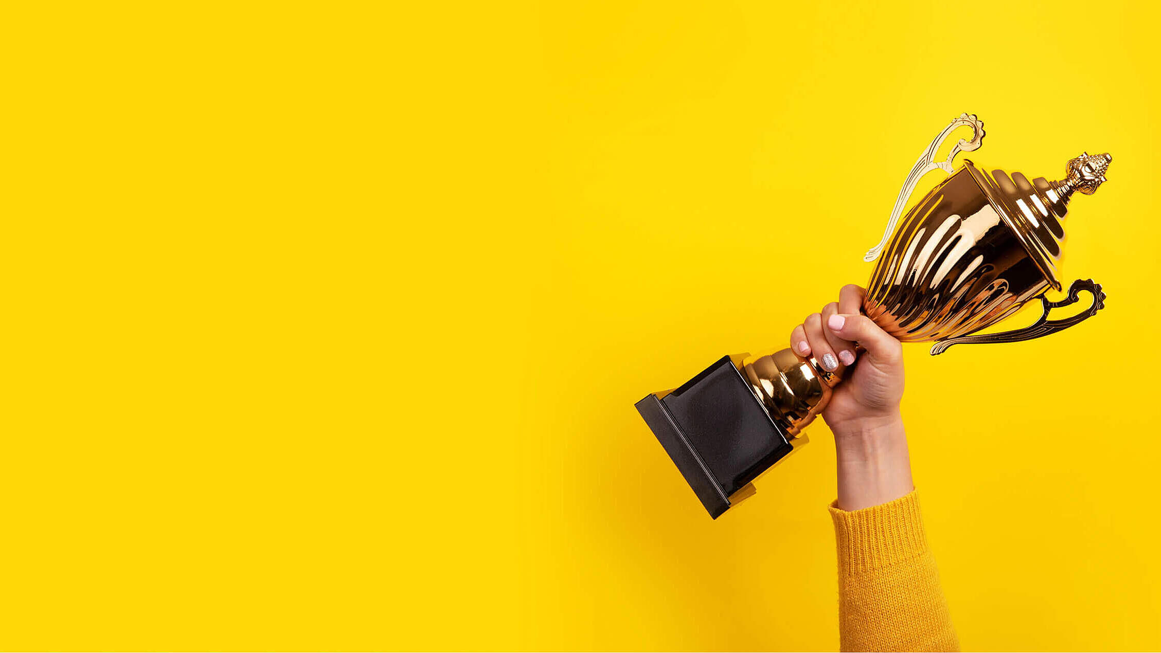 woman holding up a gold trophy cup as a winner in a competition, panoramic image