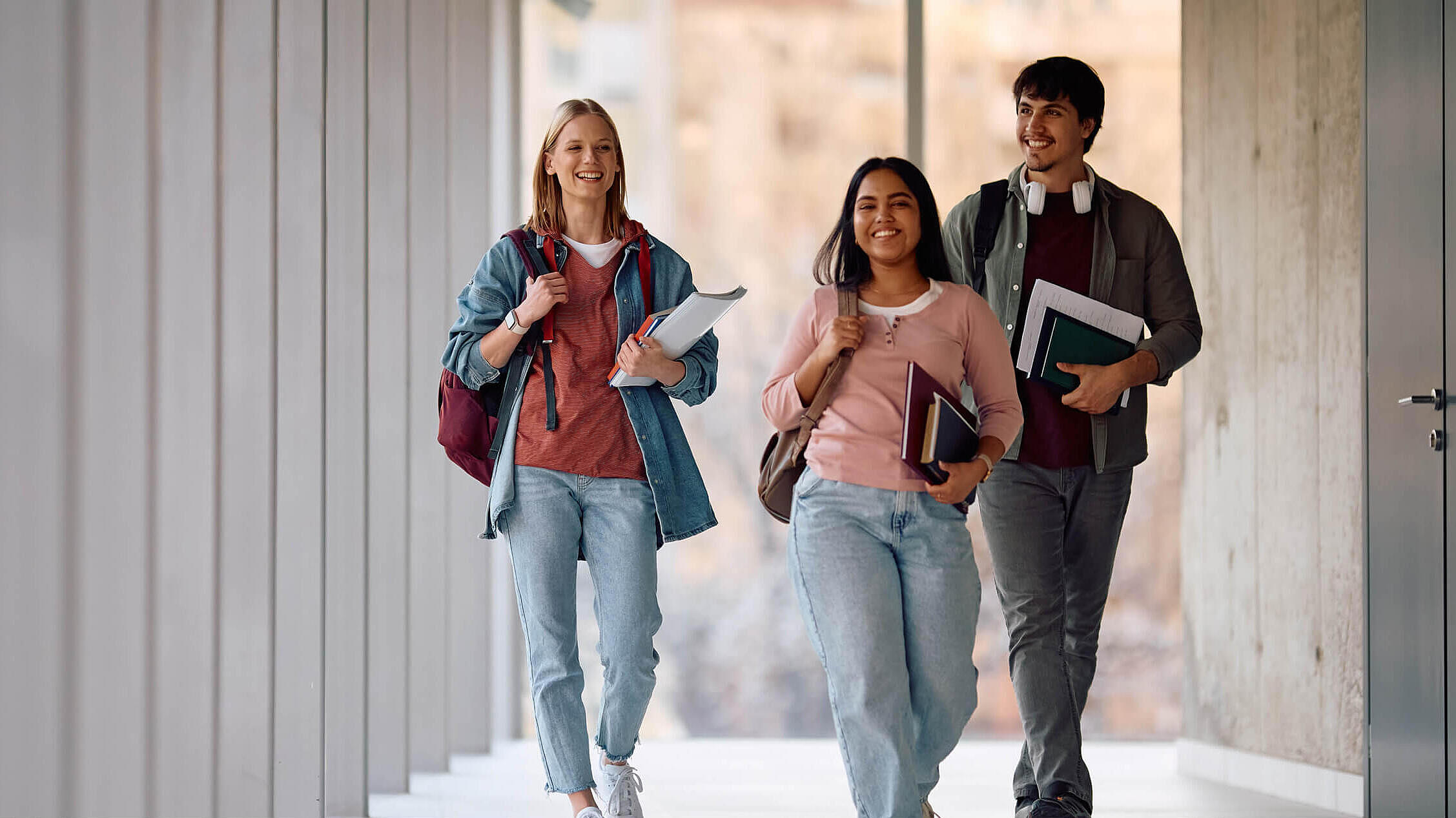 Happy student and her college friends walking through hallway.