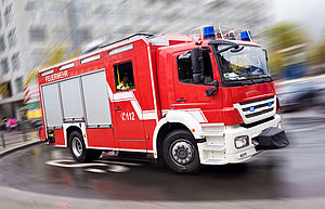 Ein Feuerwehrwagen fährt mit hoher Geschwindigkeit. Das Bild ist aufgrund der dargestellten Geschwindigkeit verwischt.