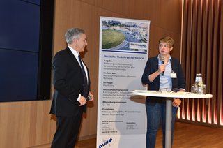 Ein älterer Herr und eine junge Frau im Gespräch an einem Stehtisch