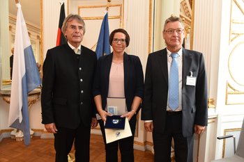 Stefanie Stark Foto: Tino Lex Eine Frau steht zwischen zwei Männer und hält eine Urkunde