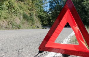 Ein Warndreieck auf einer kaputten Landstraße