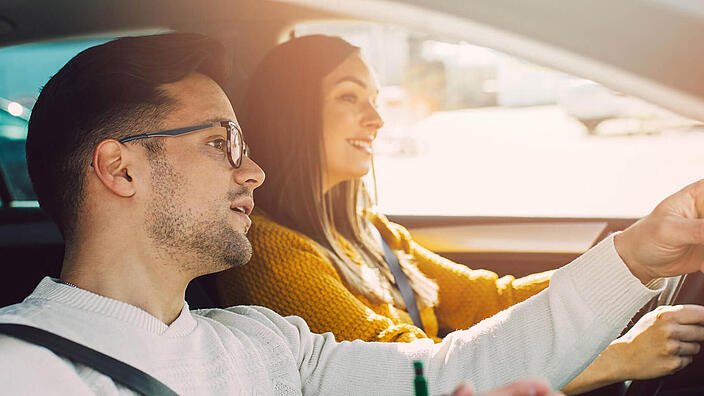 Driving school or test. Beautiful young pregnant woman learning how to drive car together with her instructor.