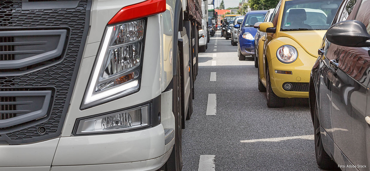 Fahrsicherheitsprogramm Lkw. Foto: Adobe Stock En grauer Lkw von vorn. Neben ihm stehen Pkw.