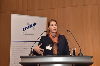 Eine Frau steht an einem Pult mit zwei Mikrofonen