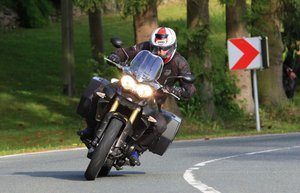 Ein Motorradfahrer fährt um die Kurve einer Landstraße