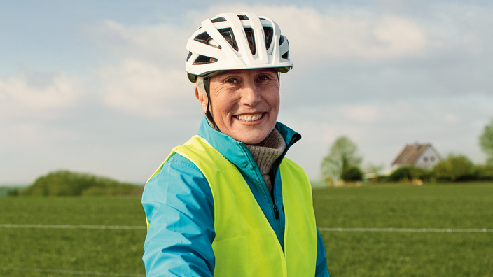 Ältere Frau mit Helm und Warnweste
