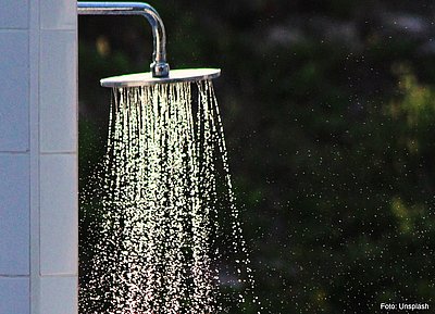 Wasser tropft aus einem Duschkopf.