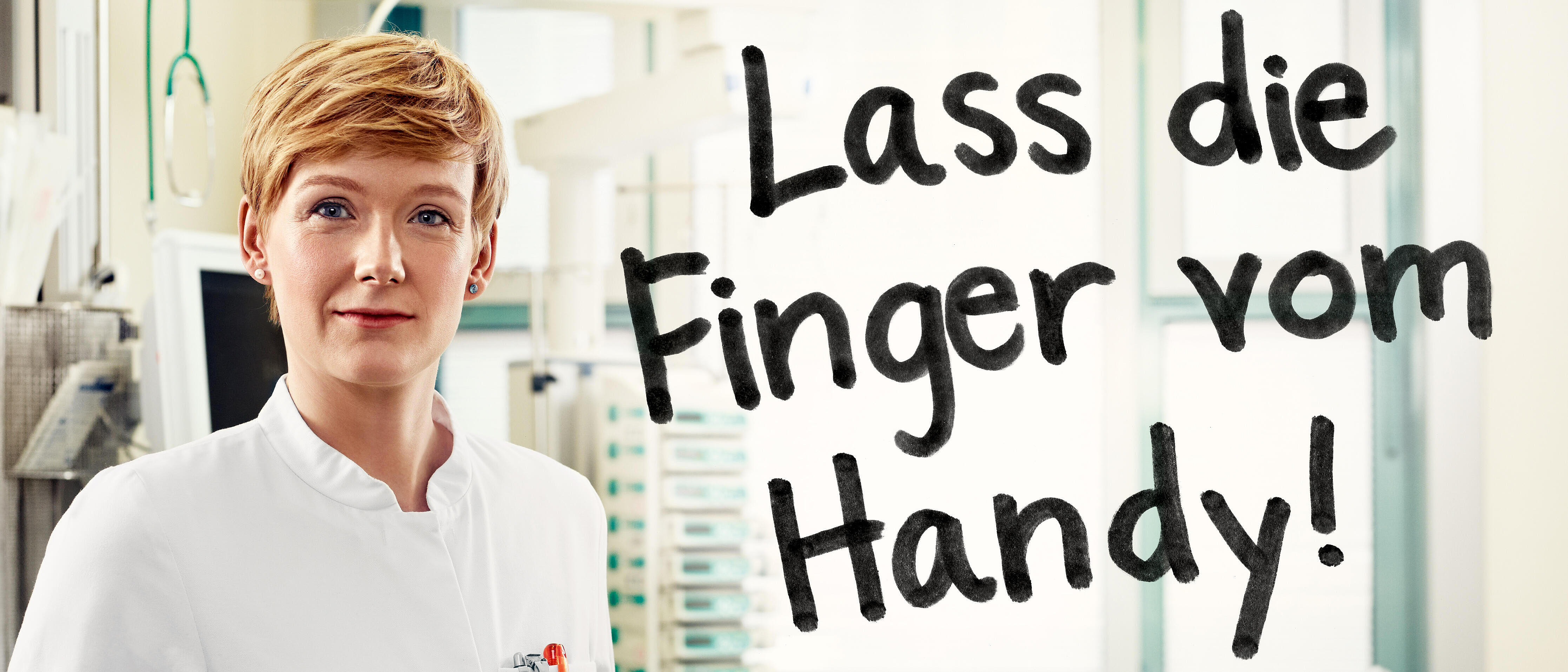 Ärztin im Krankenhaus (ggf. Notaufnahme), daneben der Spruch "Lass die Finger vom Handy!"