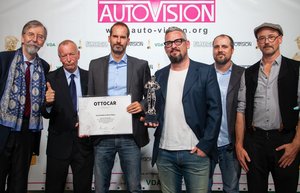 Sechs Männer stehen nebeneinander, einer hält den Preis, eine Urkunde, hoch.