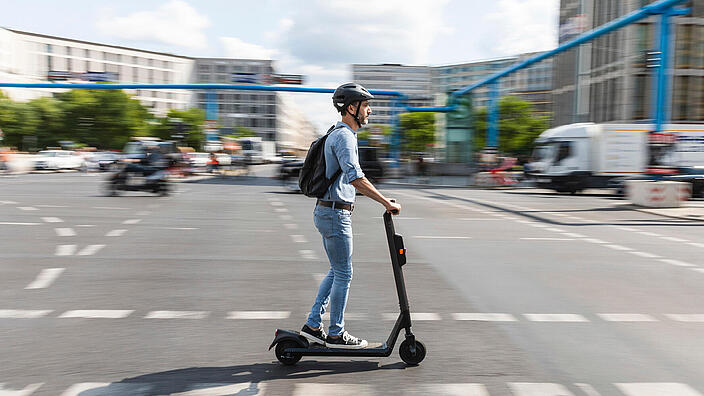 Mann mit Helm auf E-Scooter