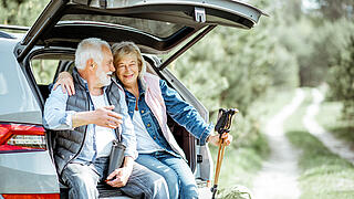 Älteres Paar sitzt im offene Kofferaum eines geparkten PKWs