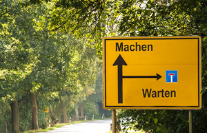 Ein gelbes Verkehrszeichend, dass in eine Richtung Machen und in die andere Richtung Warten anzeigt.