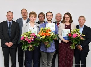 Die DVR-Förderpreisgewinner 2019 mit Blumensträußen und Urkunden in den Händen, welche gemeinsam mit den Juroren vor weißer Wand stehen.