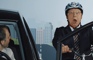  Gernot Hassknecht sitzt auf einem Fahrrad und radelt geradewegs auf eine sich öffnende Autotür zu. Er trägt einen Helm. 