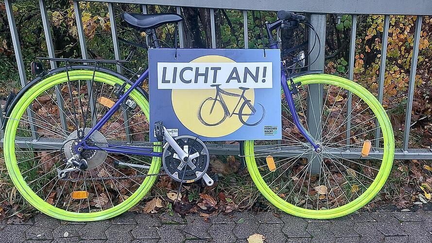 Ein Fahrrad, dessen Reifen mit leuchtender Signalfarbe besprüht sind, lehnt an einem Geländer.
