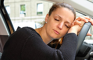 Eine Frau schläft auf dem Lenkrad eines Autos.