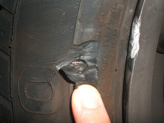 Ein Zeigefinder zeigt auf ein Loch im Reifen. Der Reifen ist kaputt. Foto: DVR