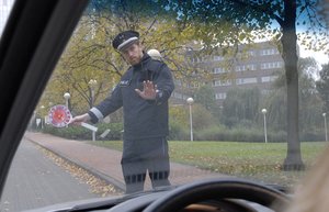 Ein Polizist hält eine Autofahrerin an.