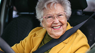 Happy senior woman driving car alone, enjoying car ride. Safe driving for elderly adults, older driver safety.