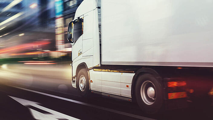 White truck moving fast on the road in a modern city with light effect